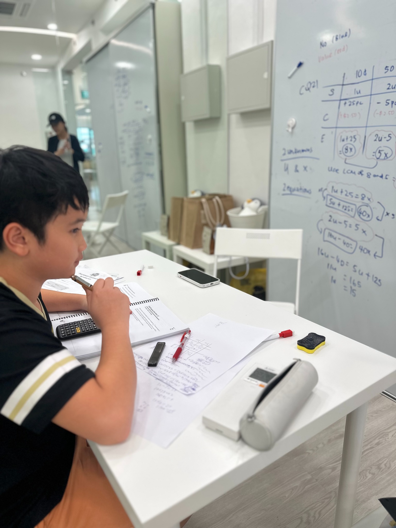 A ProgressLab student working through mathematics practice beside a whiteboard