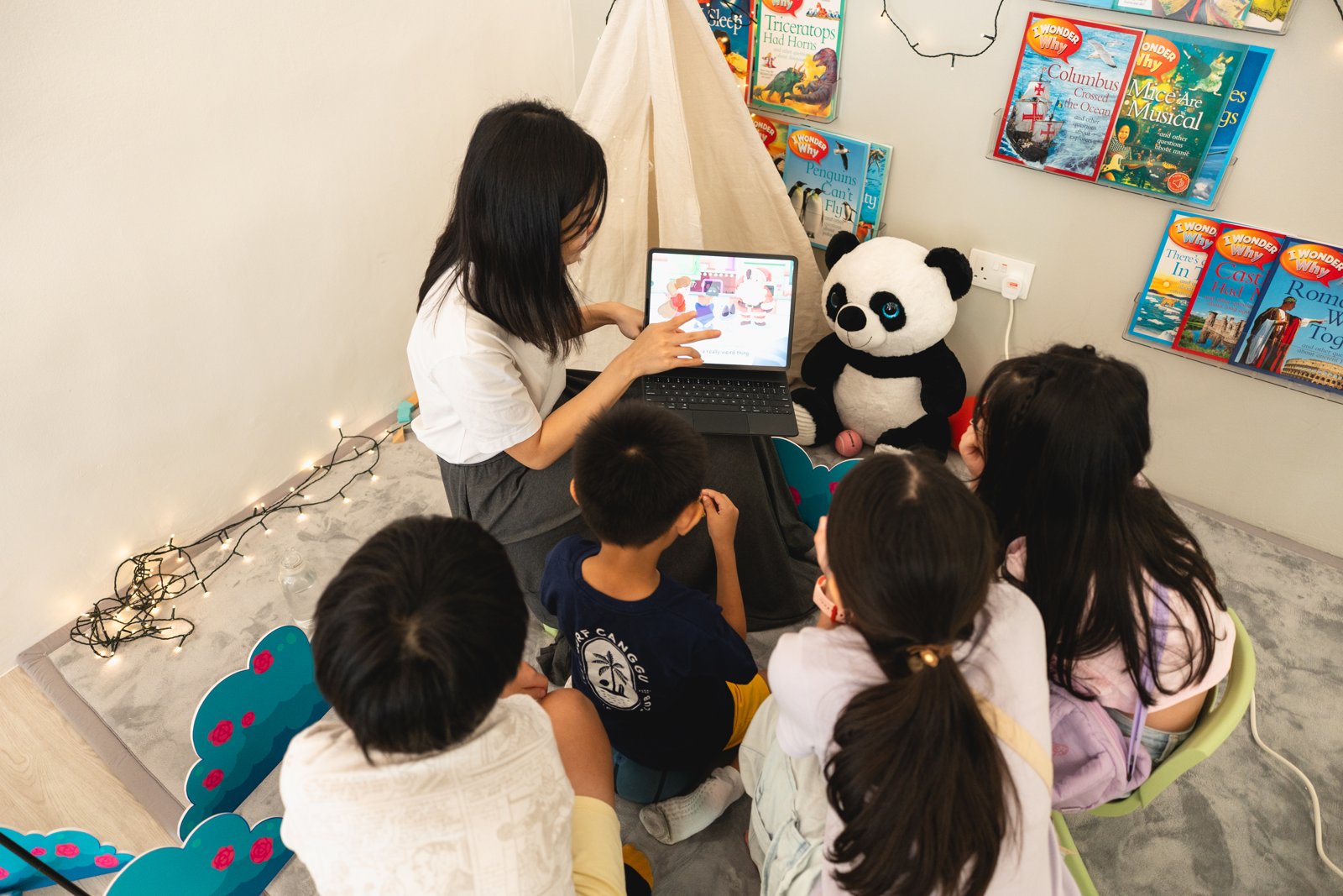 An educator guiding a small group of children through an interactive learning activity in ProgressLab’s reading corner