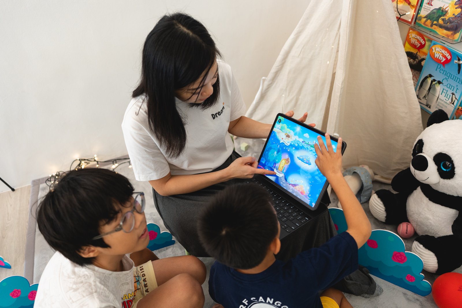 An educator guiding children through an interactive tablet activity in the reading corner