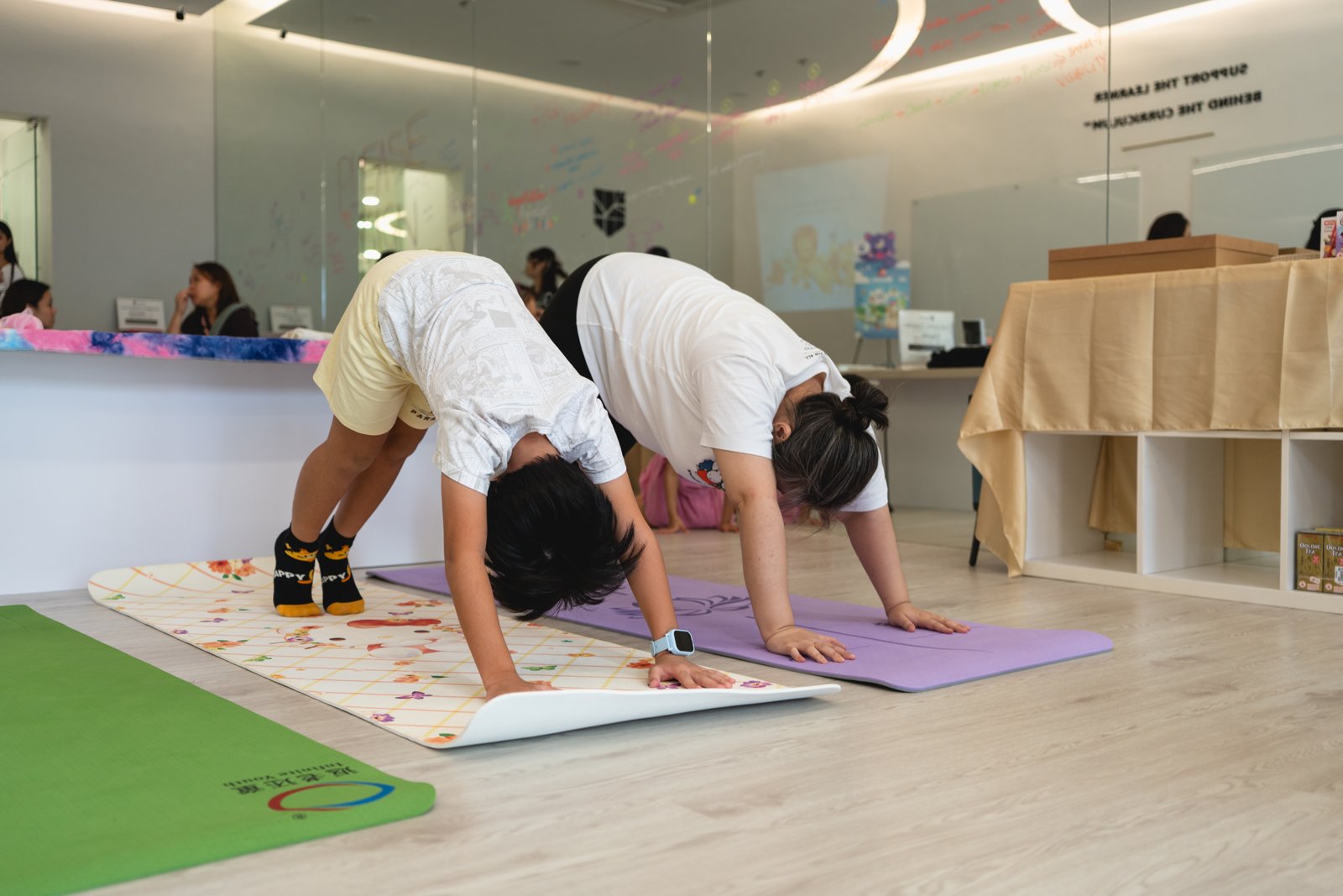 A child and instructor practising a yoga pose together at ProgressLab